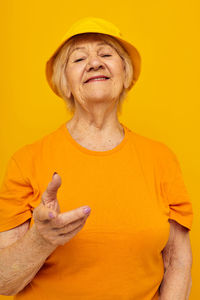 Midsection of man gesturing against yellow background