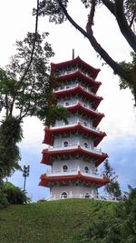 Low angle view of pagoda amidst trees and buildings against sky