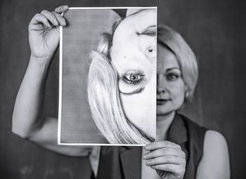 Portrait of young woman holding upside down photograph