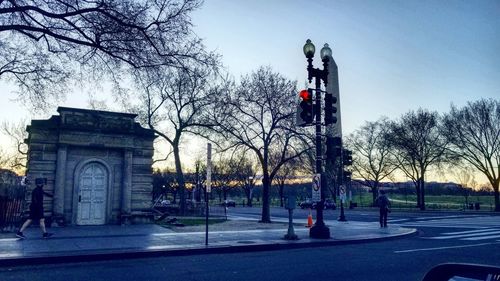 Statue on road against bare trees in city