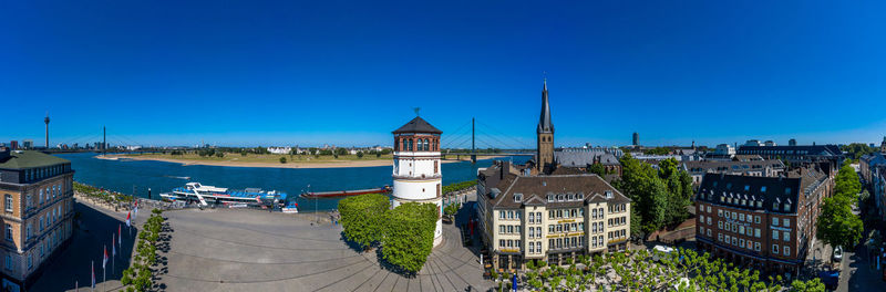 Buildings in city against clear blue sky