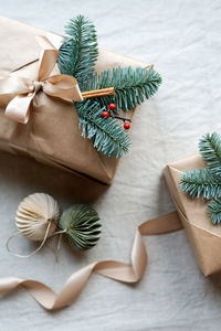 Beautifully wrapped christmas gifts with natural decor on the top lie on the table.
