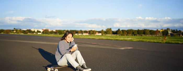 Portrait of young woman walking on road against sky