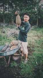 Full length of man with pineapples while standing on field