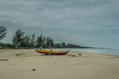 Boat moored on beach against sky