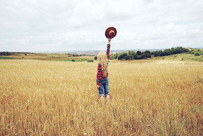 Rear view of woman standing at farm against sky