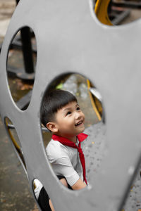 Cute boy playing while sitting on swing outdoors