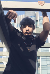 Low angle portrait of young man standing against building