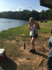 Full length of woman standing on lake against trees