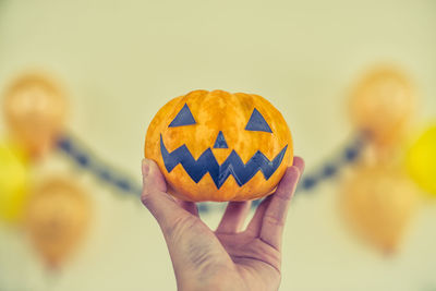 Close-up of hand holding pumpkin during halloween