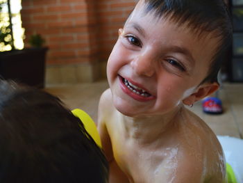 Close-up portrait of smiling boy taking bath at home