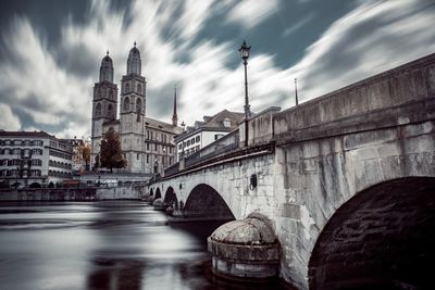 Arch bridge over river against buildings in city