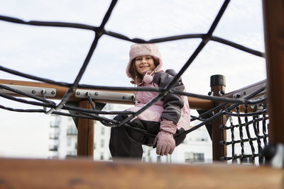 Smiling girl sitting on climbing frame