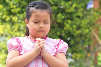 Close-up of girl praying while standing outdoors