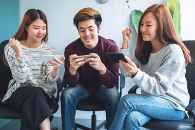 Friends using smart phones while sitting at school