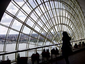 Woman looking at river through glass window