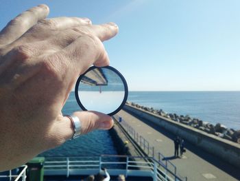 Close-up of man holding camera against sea