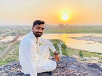 Portrait of young man standing against sky during sunset