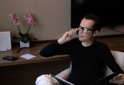 Young man using mobile phone while sitting on table