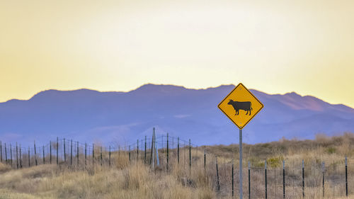 Road sign against mountain during sunset