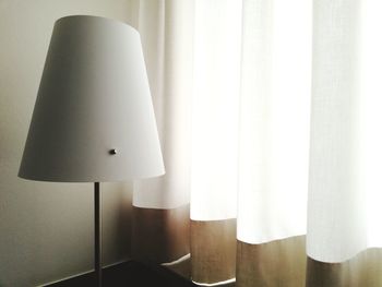 Electric lamp hanging against white wall at home