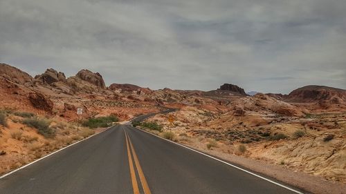 Road leading towards mountains against sky