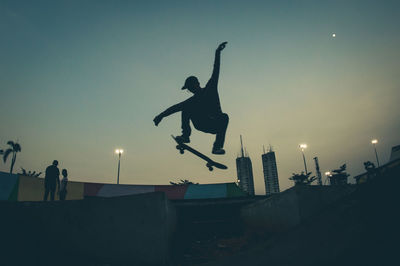 Silhouette man jumping against sky at sunset