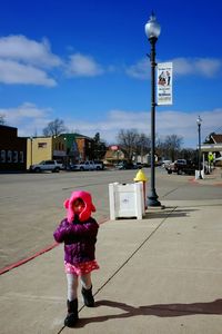 Woman standing on road against cloudy sky