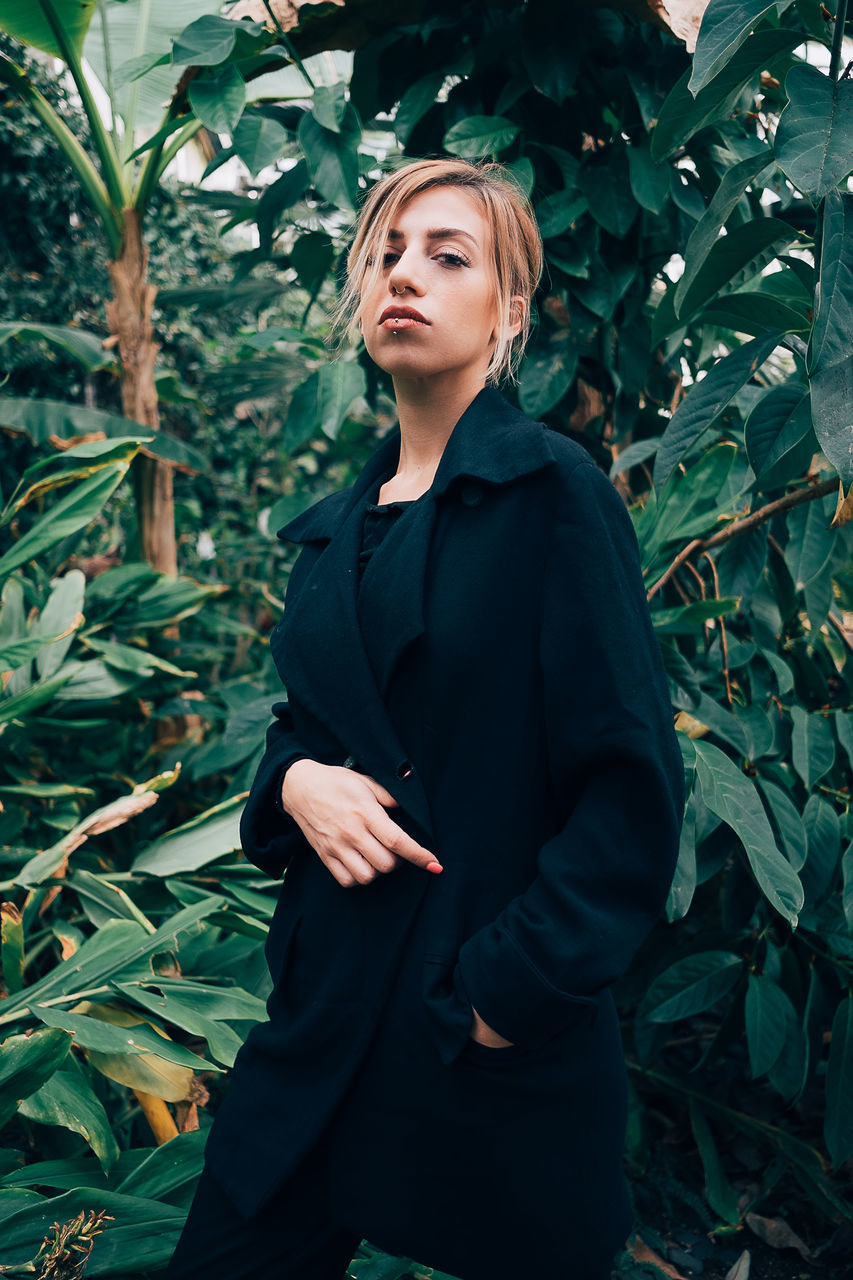 one person, plant part, leaf, standing, young adult, plant, young women, real people, three quarter length, growth, leisure activity, lifestyles, nature, clothing, looking, looking away, day, front view, beautiful woman, outdoors, leaves, hairstyle, contemplation