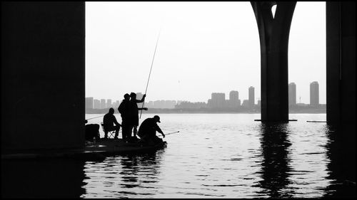 Silhouette men in city against clear sky