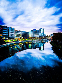 Bridge over river by buildings against sky in city