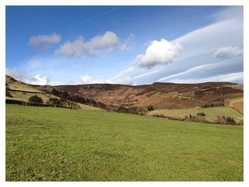 Scenic view of grassy field against cloudy sky