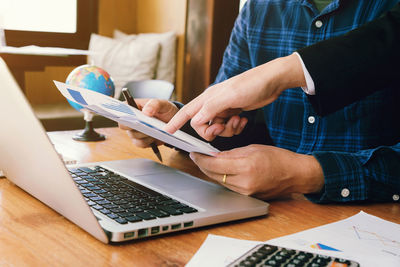 Midsection of man using laptop on table