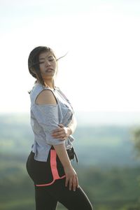 Young woman standing on mountain against clear sky