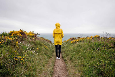 Rear view of woman standing on field against sky