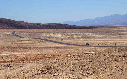 Asphalt road leading through steaming hot landscape of death valley national park