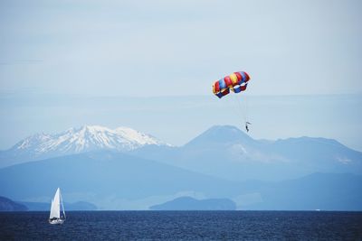 Parachute flying over mountains against sky