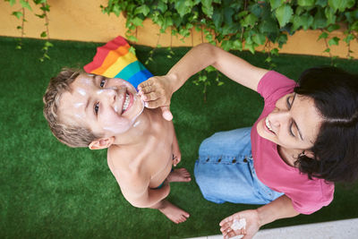 A mother puts sun cream on her son.