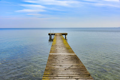 Wooden jetty on pier over sea against sky