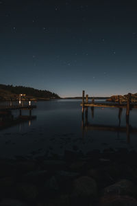Pier over lake against clear sky at night