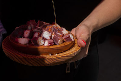 Close-up of person holding ice cream cone against black background
