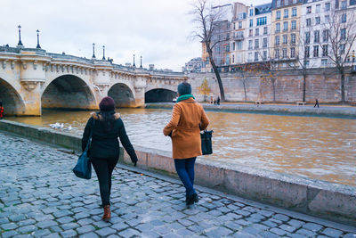 Rear view of people walking on bridge over canal