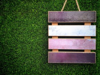 Empty wooden label board on artificial green grass background