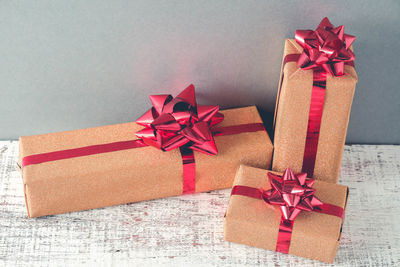 Close-up of christmas presents on wooden table against gray wall