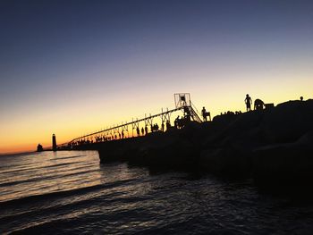 Silhouette of bridge over river against sky