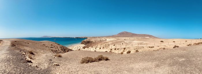 Scenic view of beach against clear blue sky