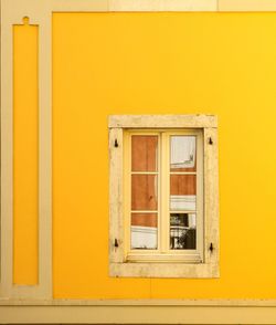 Closed window of yellow wall of house