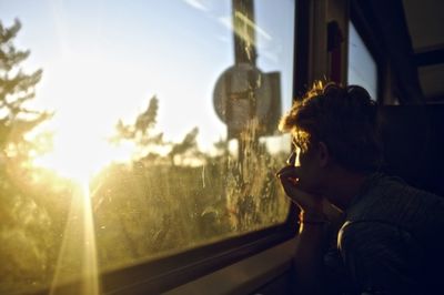 Side view of young man looking through window in train