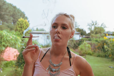 Young woman smoking marijuana joint while standing outdoors