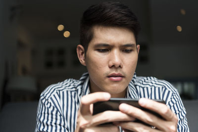 Close-up of young man using smart phone while siting at home